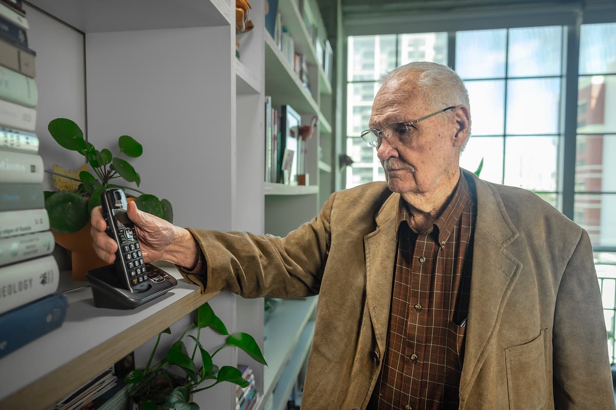 An older man comfortably reaching for his Community Phone handset, using it as easily as he always has.